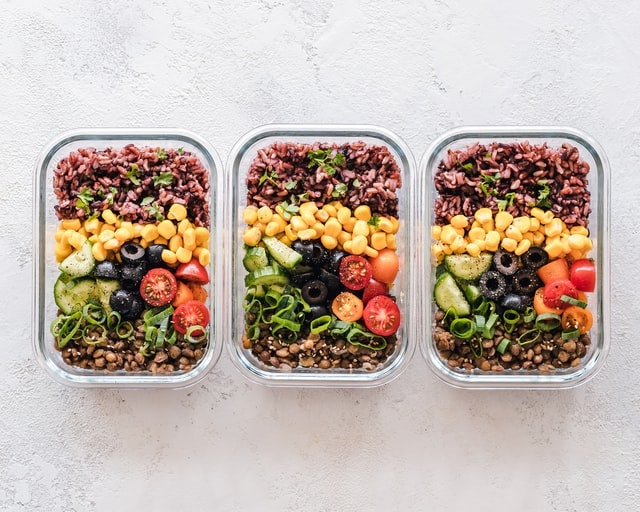 Three plastic containers of food on a counter