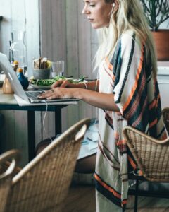 Blonde woman working at a table with a laptop