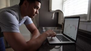 Man looking at investing graph on a laptop