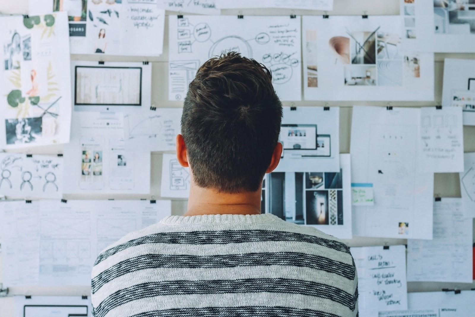 Man examining papers stuck to a whiteboard