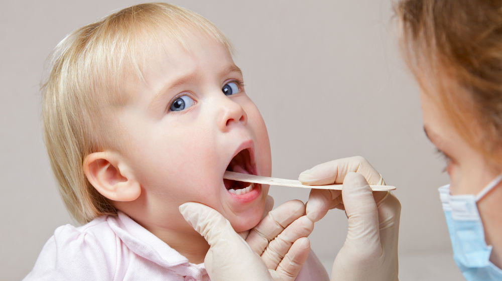 doctor checking child's throat with tongue depressor