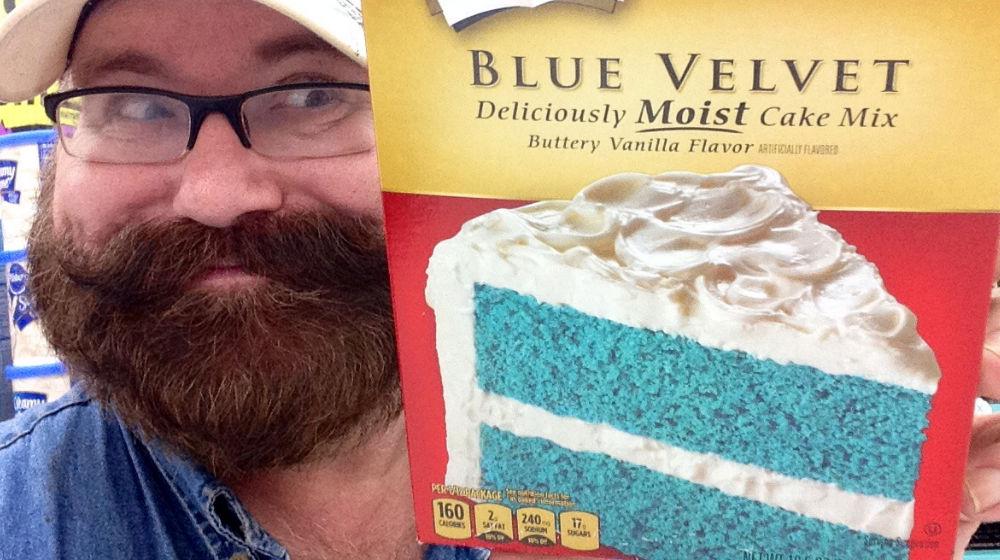 Bearded guy holding up box of blue velvet cake mix