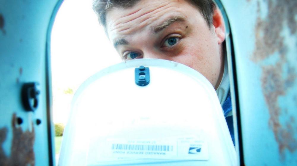 suspicious guy looking into mailbox