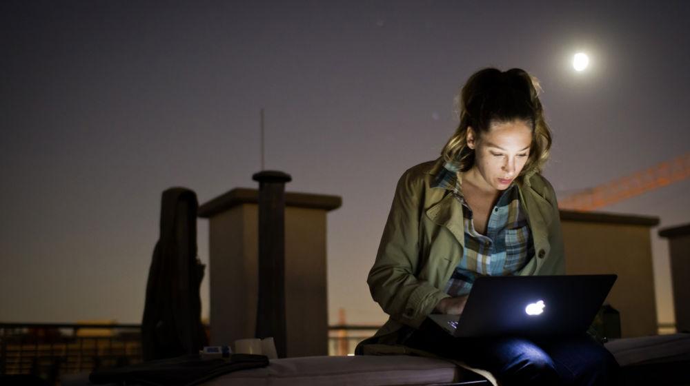 women with laptop computer working outside in moonlight