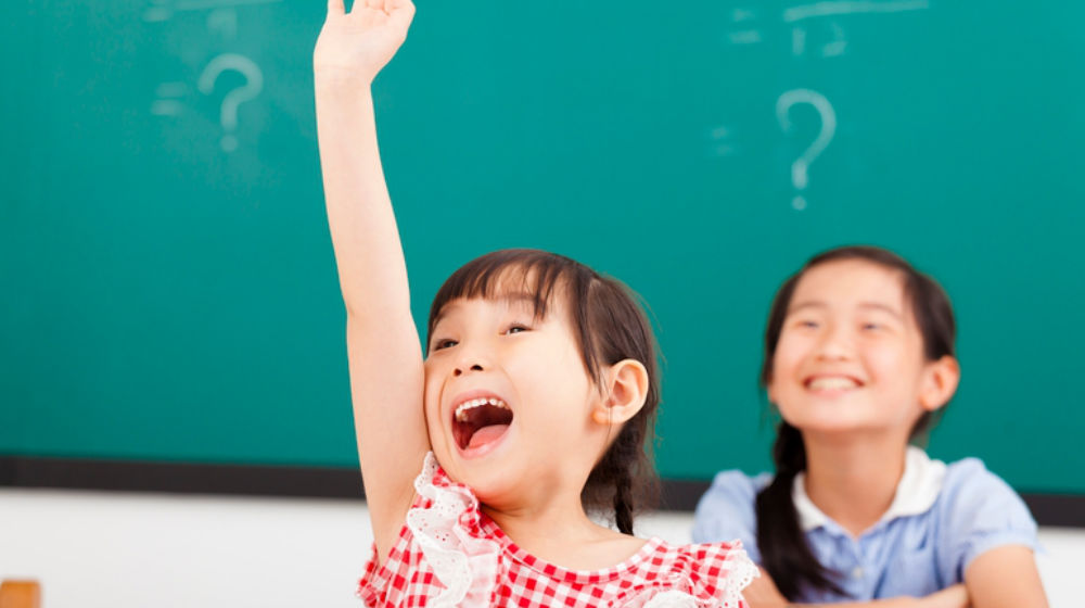little girl raising hand in class