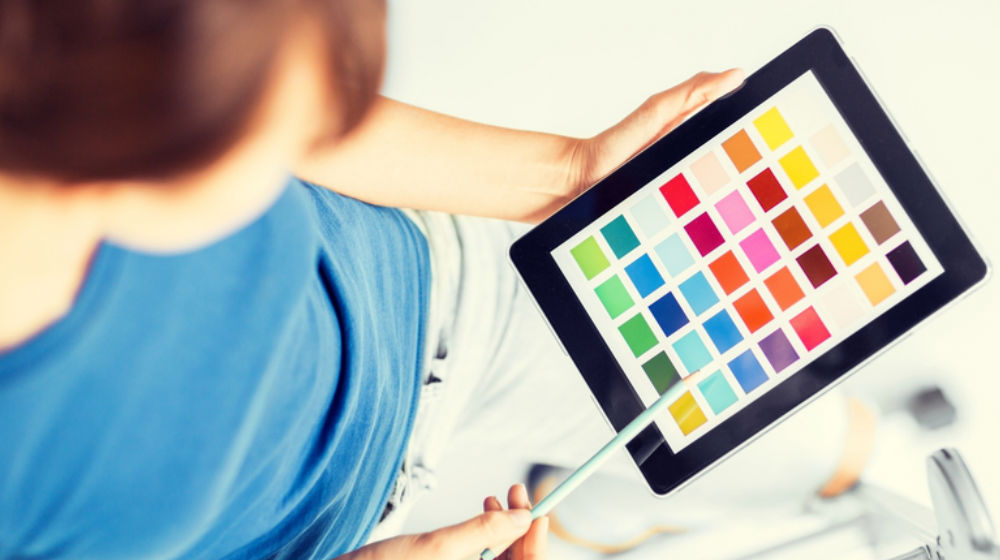 designer looking at color swatches on tablet to illustrate .design domain extension