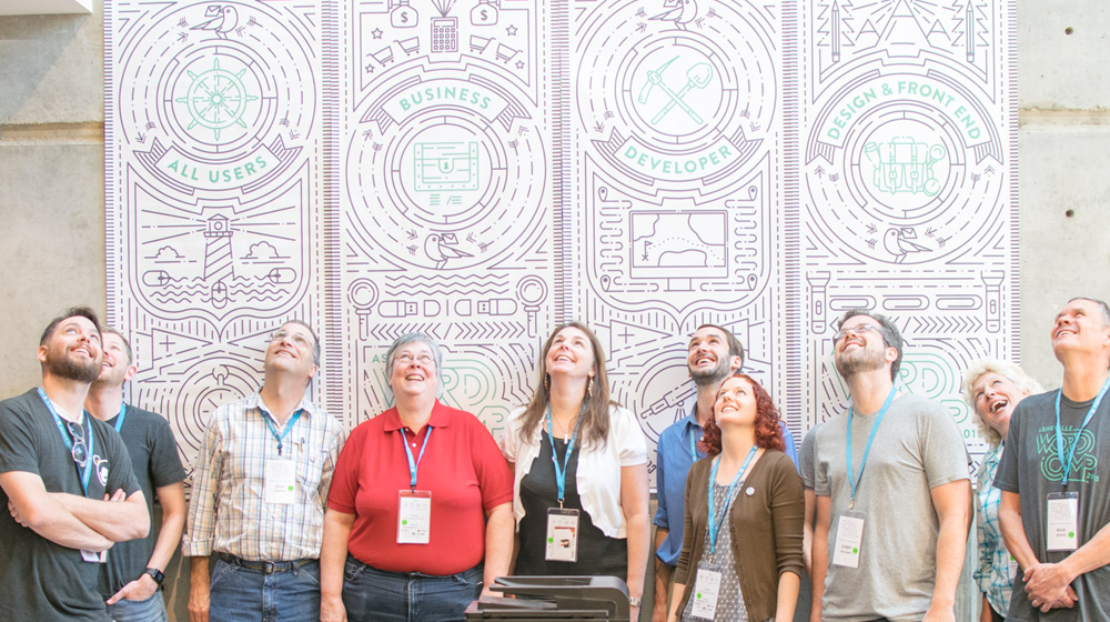 Happy participants in a row looking up and smiling at WordCamp Asheville
