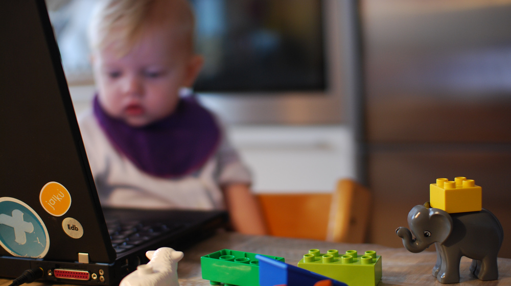 Baby in front of a computer to represent working from home.