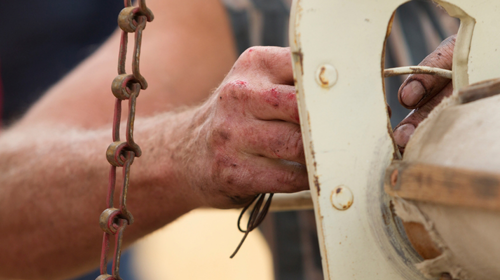 Dirty hands working machinery to represent importance of coming up with solid strategy and then doing the work to get there