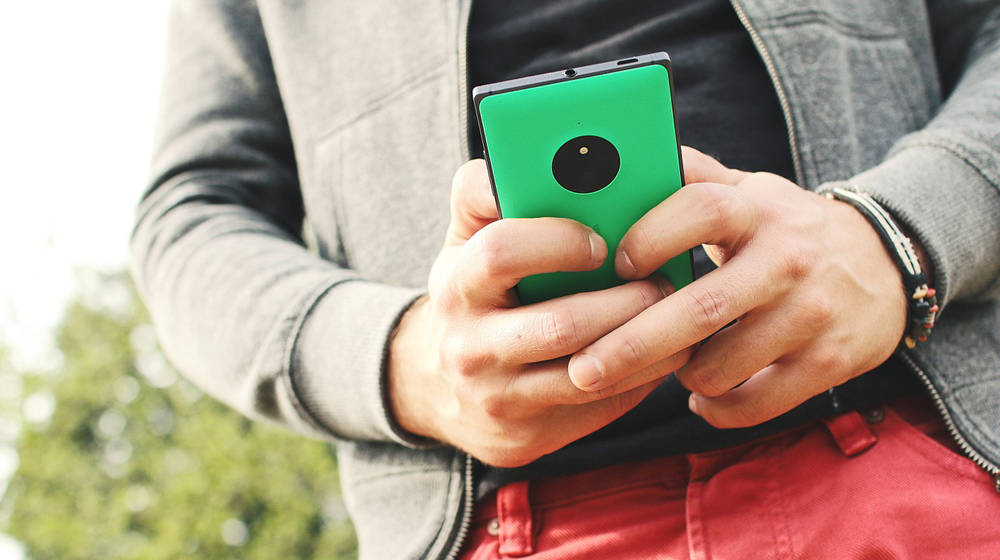 man holding mobile phone to represent importance of mobile friendliness when considering a website redesign