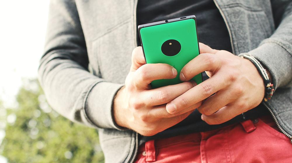 man holding mobile phone to represent importance of mobile friendliness when considering a website redesign