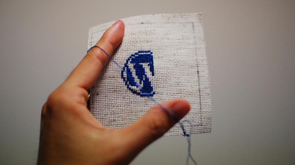 stitching wordpress logo in blue thread to represent participating in the wordpress community