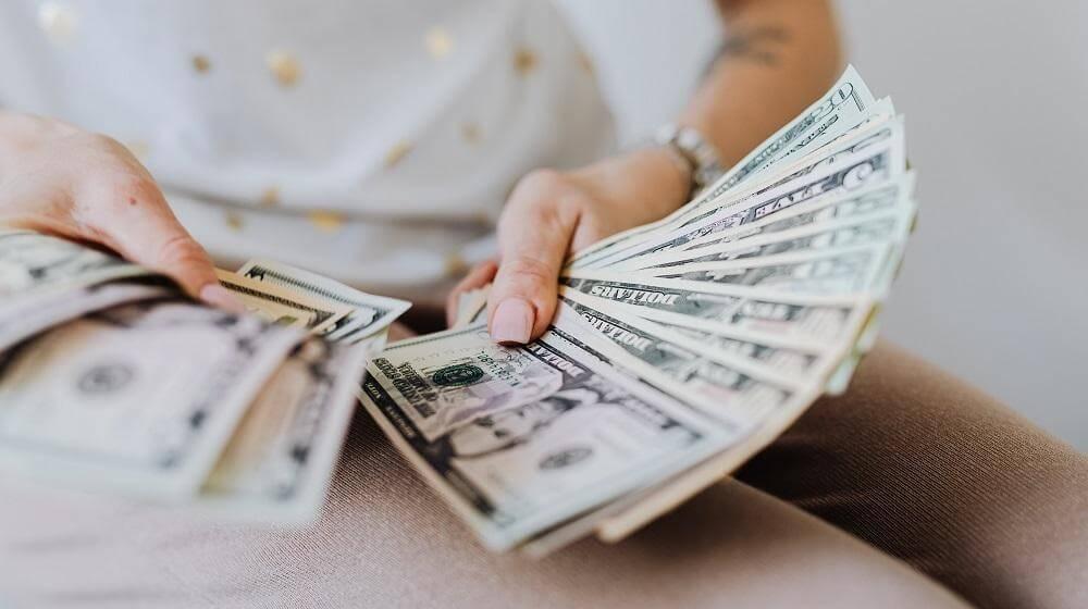 Woman holding fanned-out money on her lap