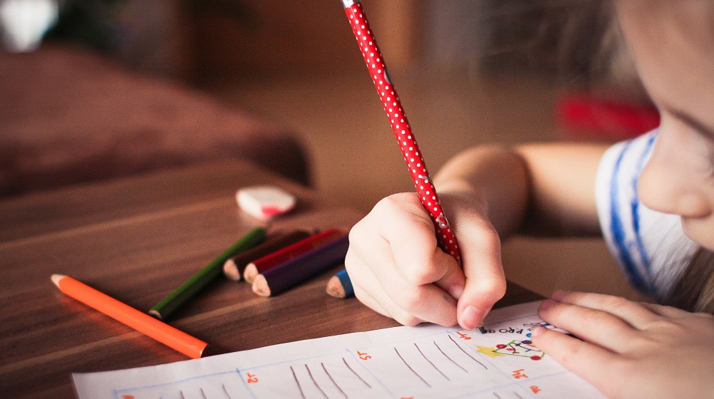 Small Child Doing Homework With A Red Pencil Illustrating How To Run A Business With Kids At Home