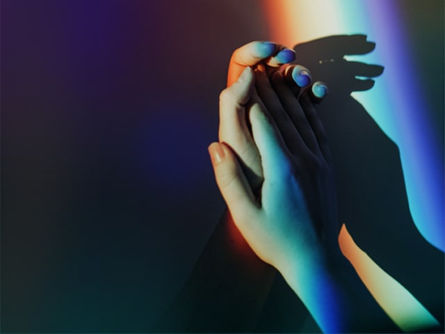 Hand together with rainbow light