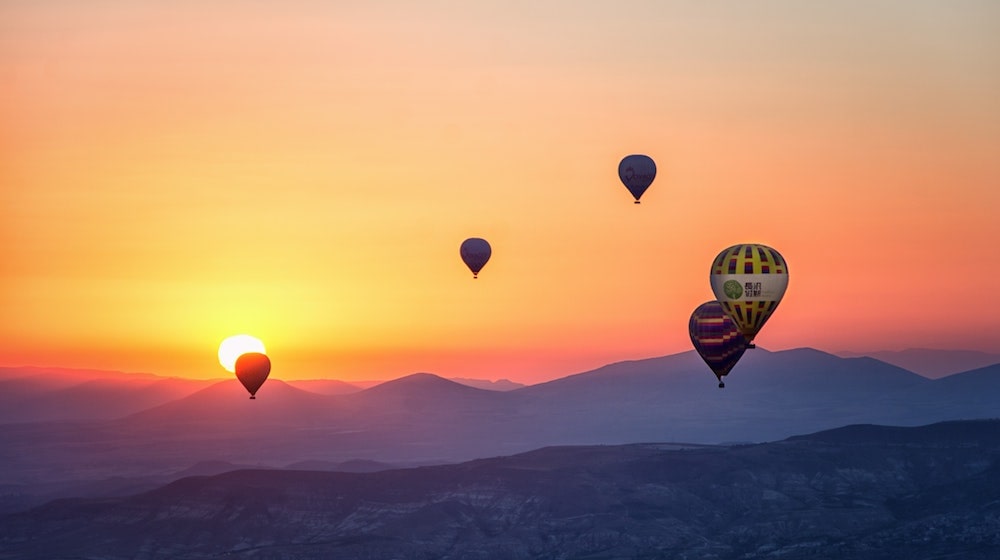 Hot air balloons against a sunset and mountains