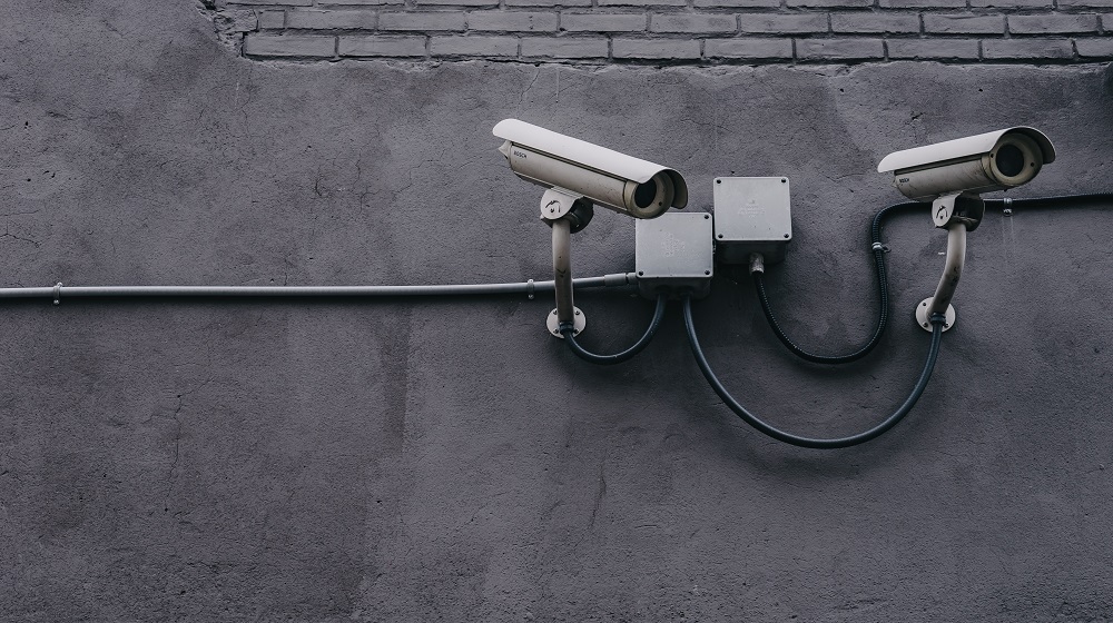 Two Security Cameras On A Concrete Wall