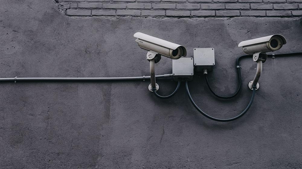 Two Security Cameras On A Concrete Wall
