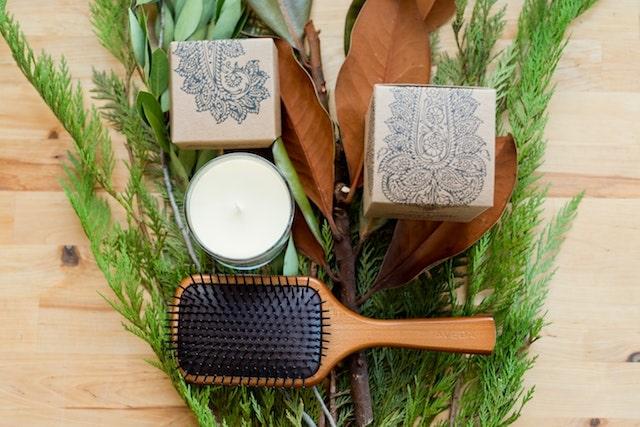 Brush and candle on table with greenery