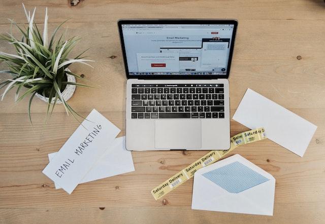 Computer on desk with envelope and plant