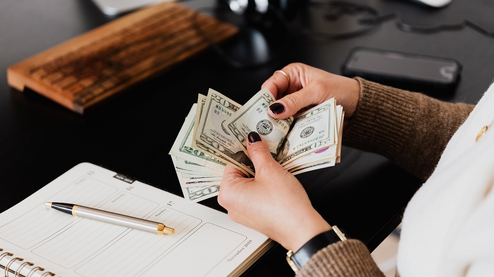 Woman Counting Money On Desk