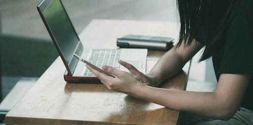 Person searching online with computer and smartphone
