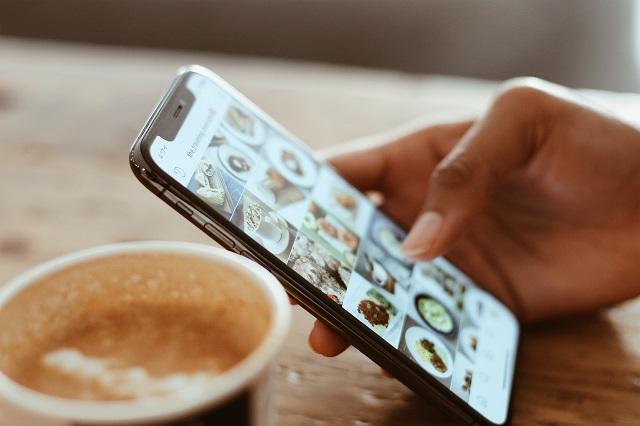 User scrolling through social media on phone while having coffee