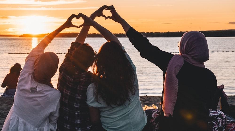 Four friends looking at sunset on beach