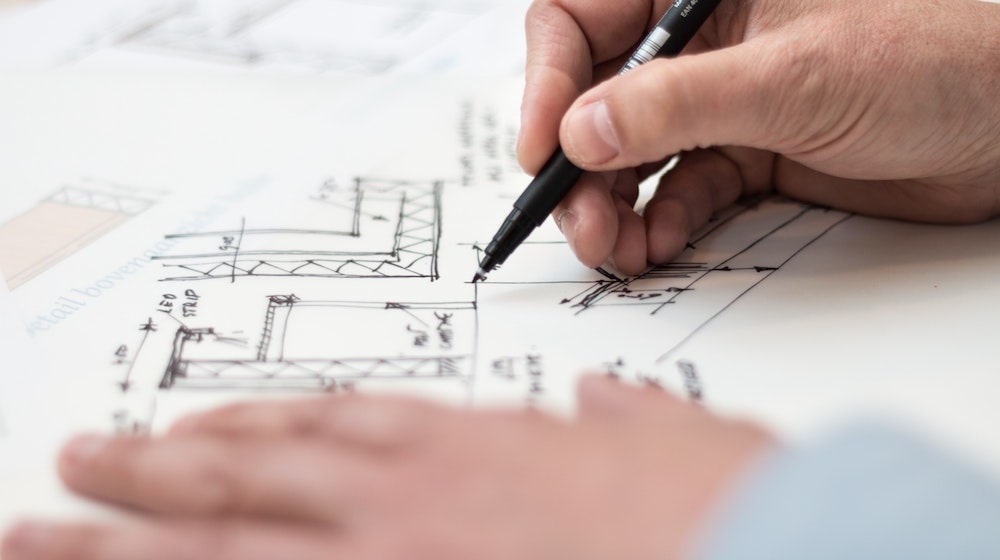 Person drawing a blueprint with pen