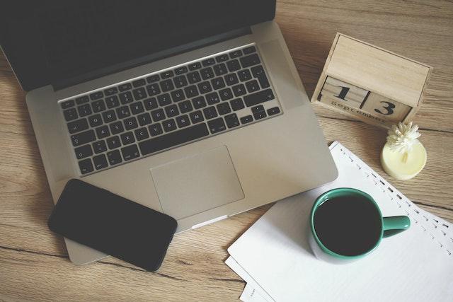 Computer open with coffee cup and desk calendar