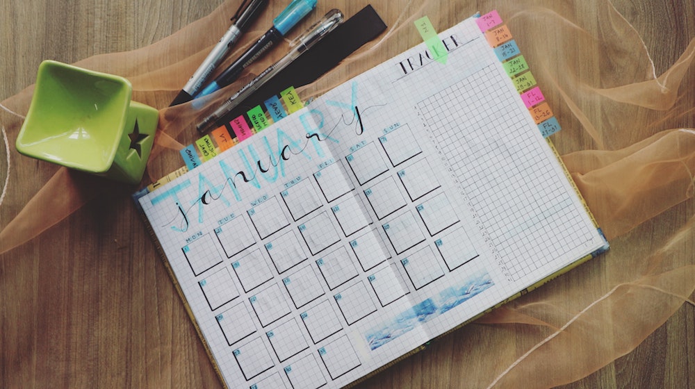 Planner open to January with colorful tabs and pens