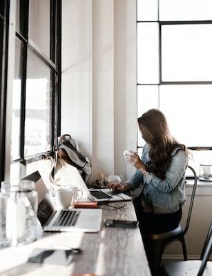 Woman blogging at coffee shop]