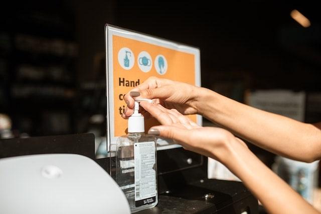 Woman using hand sanitizer at store entrance