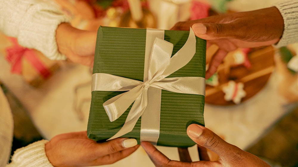 Two people exchanging a gift in green wrapping paper