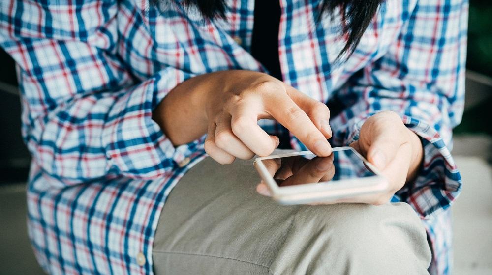 Person using smartphone on lap