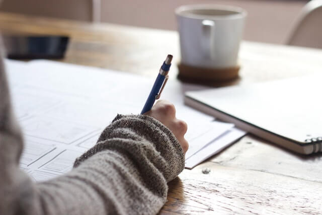 Person writing on paper with pen.