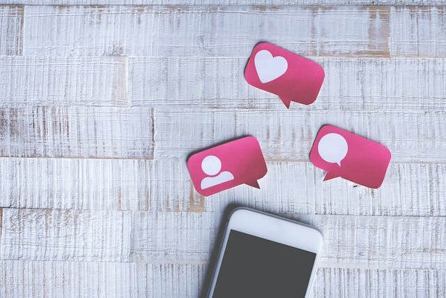 White cell phone with images of likes hearts and comments]