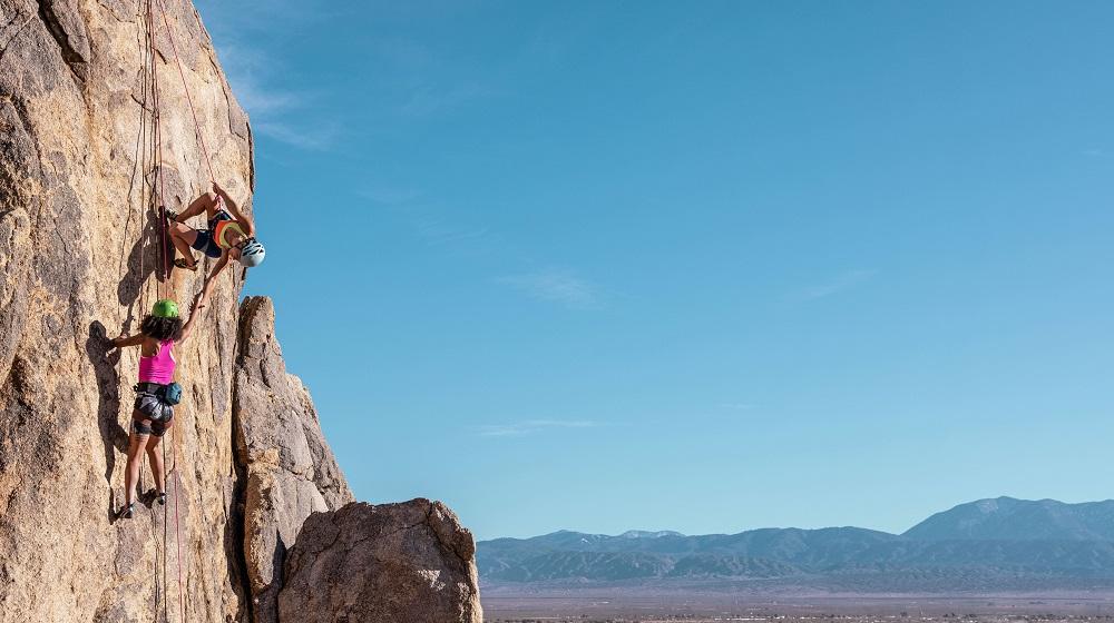 She Moves Mountains founder Lizzy VanPatten helping climber on rock face