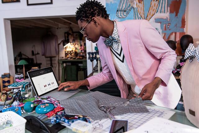 Moziah Bridges checking tablet while sewing bow ties