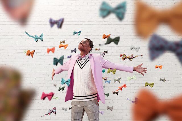 Moziah Bridges with arms out surrounded by falling bow ties