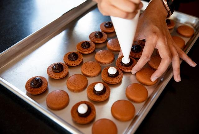 Anita Lee piping filling onto baked macarons