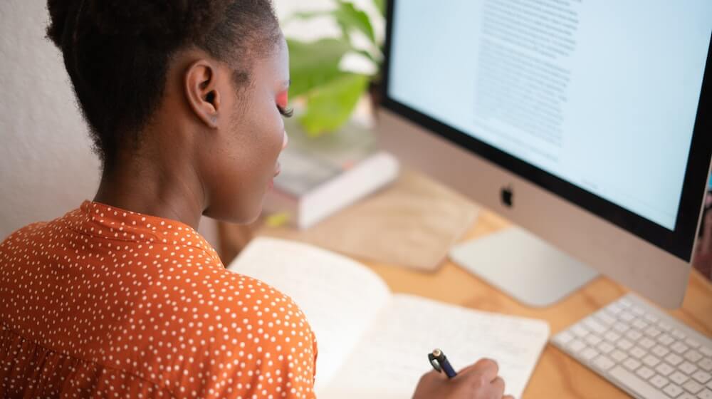 Woman sitting at computer taking notes