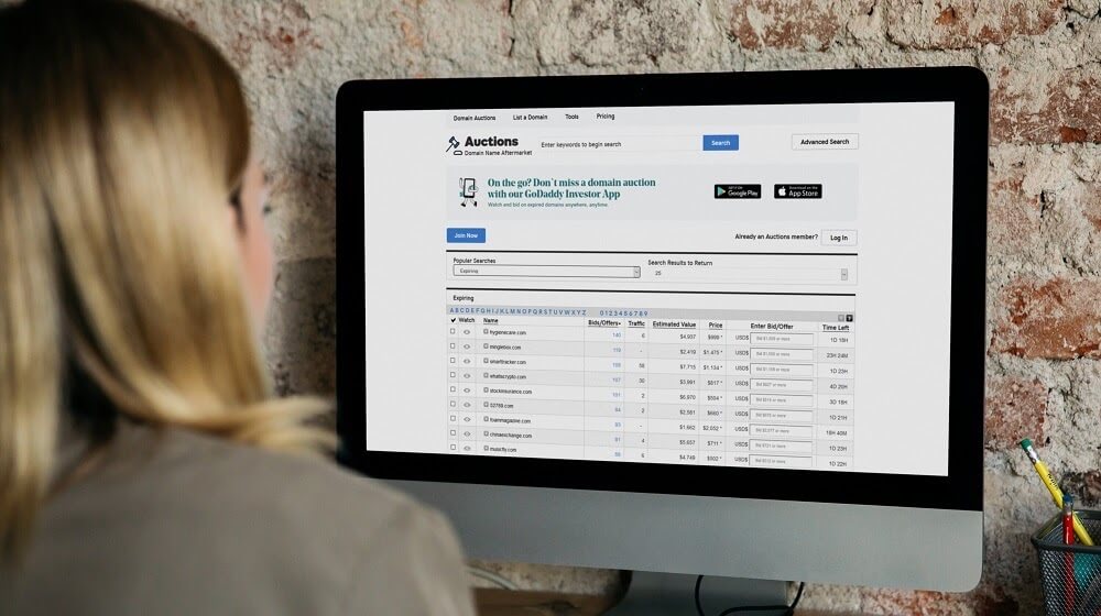 Woman browsing expiring domain names on GoDaddy Auctions site