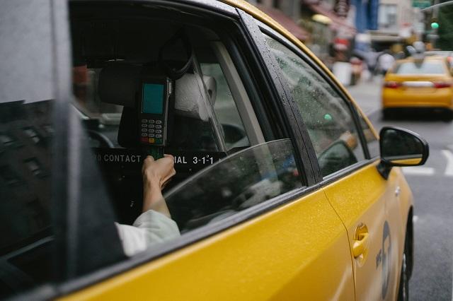 Passenger using a credit card processing machine in a yellow taxi cab