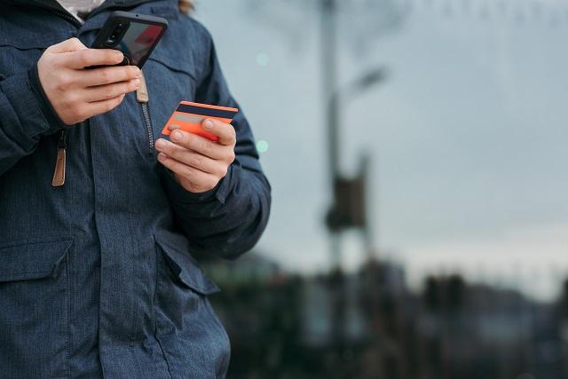 Person using credit card with their mobile phone