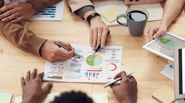 Group studying printed data on a conference table