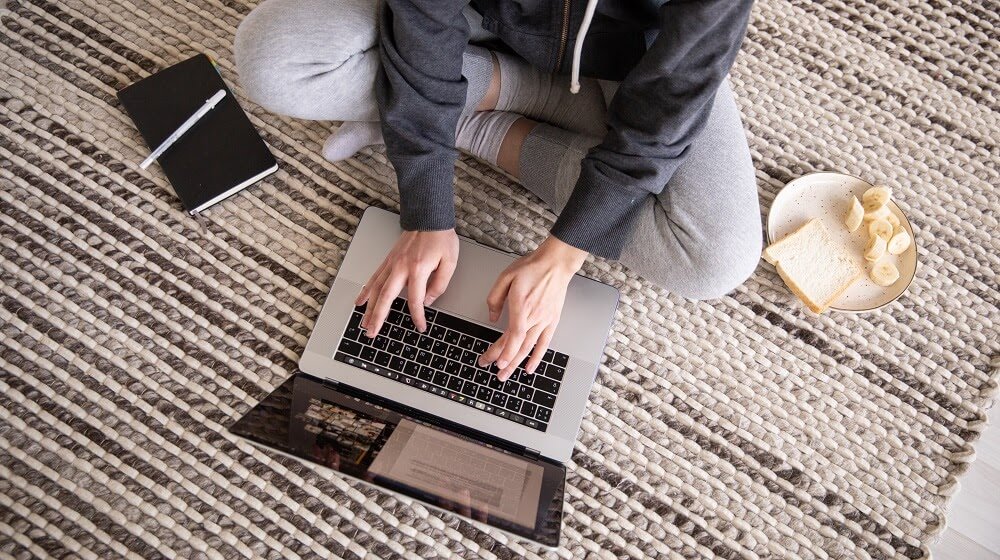 Person sitting on floor working with laptop