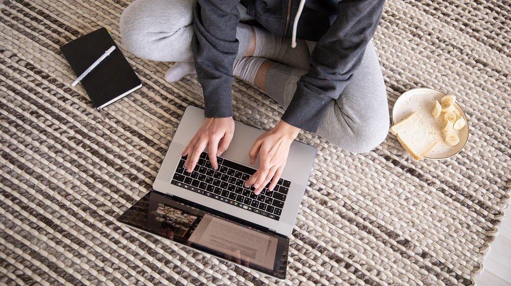 Person sitting on floor working with laptop