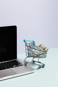 Shopping cart with cash resting on a laptop