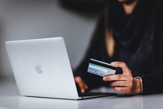Person at computer holding a credit card